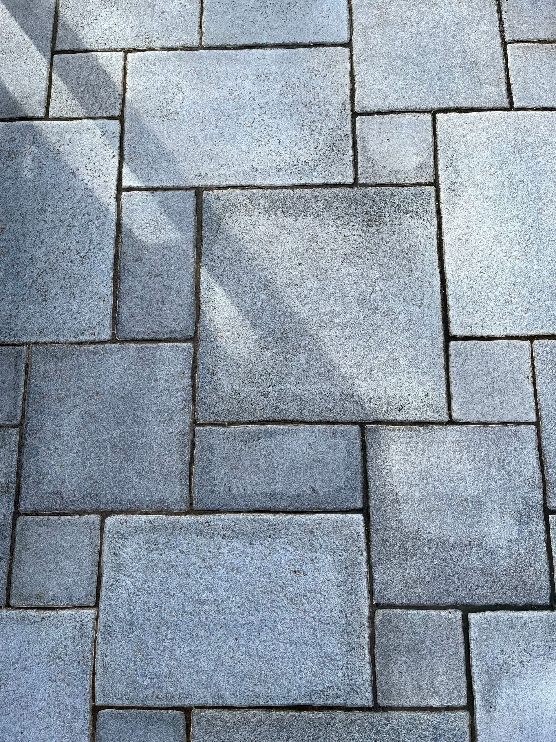 Close-up of a geometric concrete paver pattern with distinct shadows casting an abstract look.